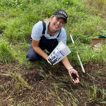Load image into Gallery viewer, Female farmer in a field holding a bag of Worm Manure before it is applied to the soil