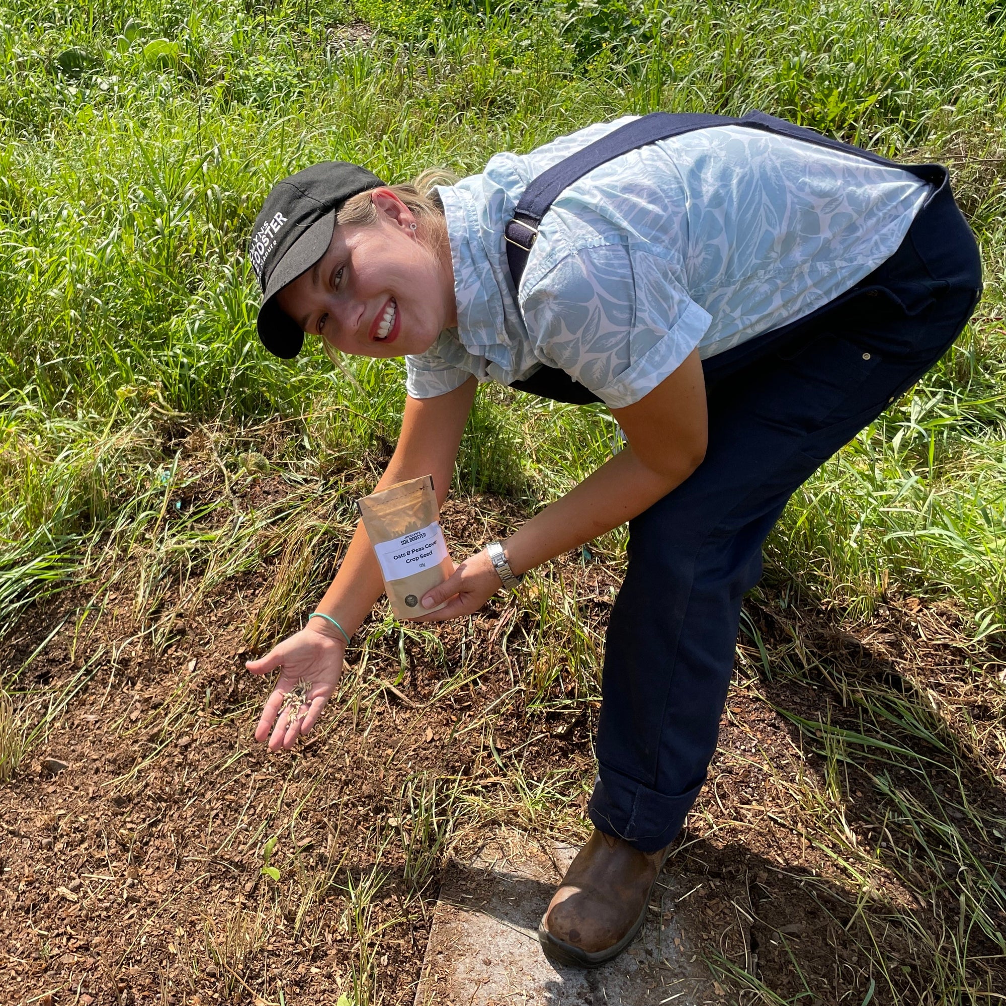 Female farmer bent over in field holding seeds in hand