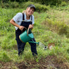Female farmer in field smiling and holding a watering can